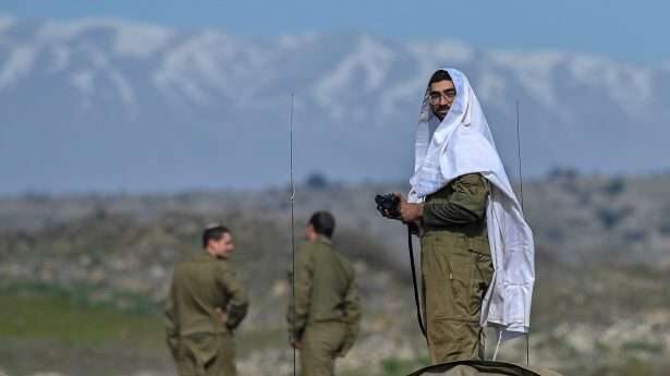 De dag goed beginnen. Een Israëlische parachutist in zijn gebedsmantel voordat de ochtend­oefeningen beginnen.