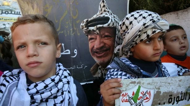 Palestijnse kinderen in Hebron houden posters vast ter gelegenheid van de 18e verjaardag van de dood van Yasser Arafat. 