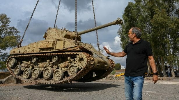 Arbeiders plaatsen een oude tank bij een gedenkplaats als onderdeel van de herdenking van de 50e verjaardag van de Jom Kippoer-oorlog. 